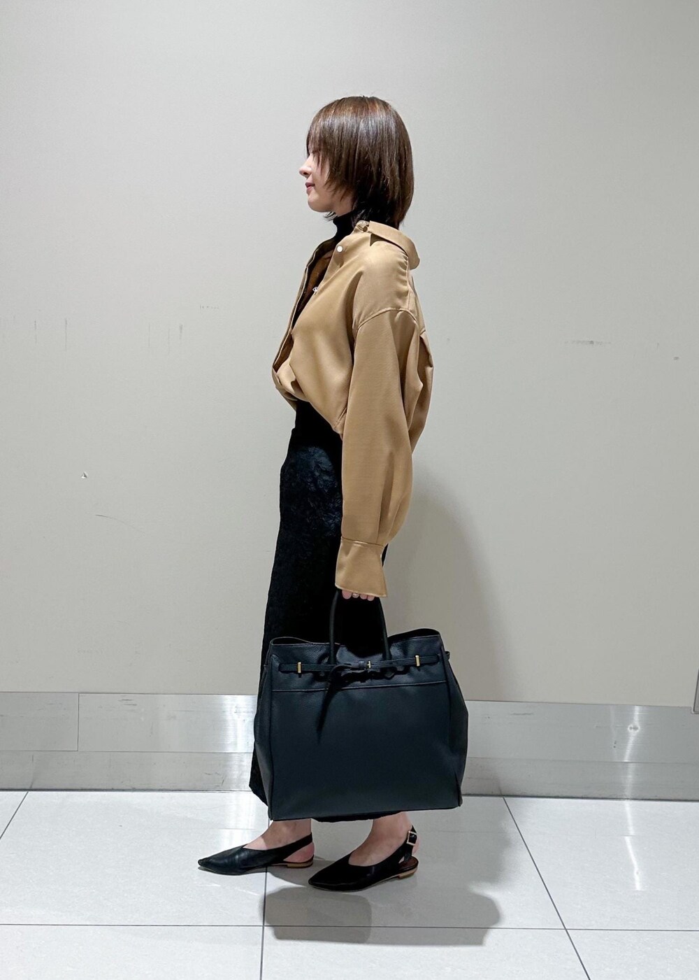 ブラック系のトートバッグ、ベージュ系のシャツ/ブラウス、ブラック系のニット/セーターを着用したレディースの秋コーディネートの2枚目の写真