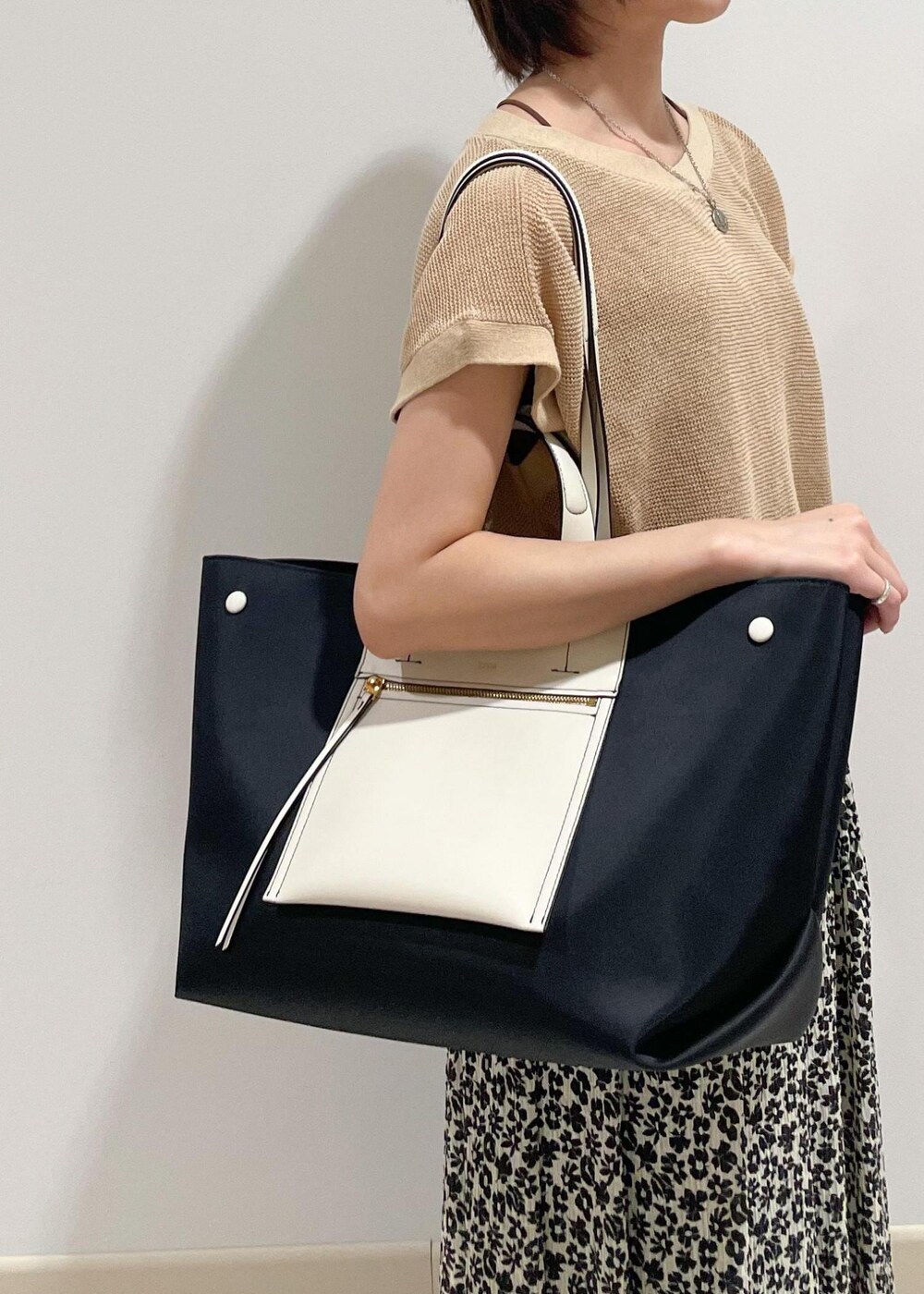 ブラック系のハンドバッグ、ベージュ系のTシャツ/カットソー、ブラック系のスカートを着用したレディースの夏コーディネートの6枚目の写真