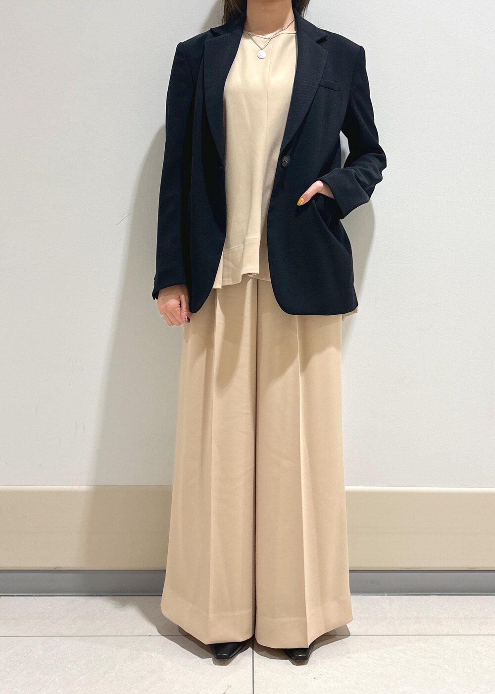 ブルー系のテーラードジャケット、ブラック系のパンプス、ブラック系のトートバッグを着用したレディースの春コーディネートの4枚目の写真