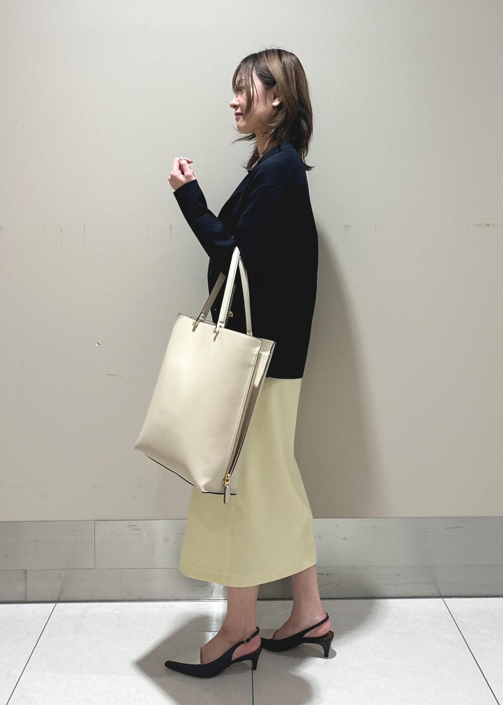 ブラック系のパンプス、ベージュ系のスカート、ピンク系のTシャツ/カットソーを着用したレディースの春コーディネートの2枚目の写真