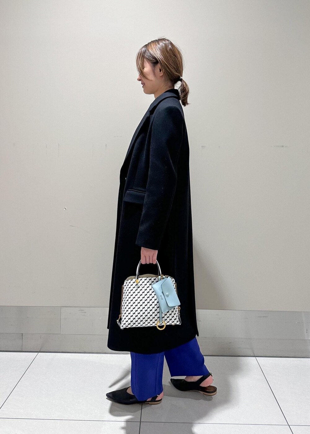 ホワイト系のショルダーバッグ、ブラック系のチェスターコート、グレー系のシャツ/ブラウスを着用したレディースの冬コーディネートの2枚目の写真