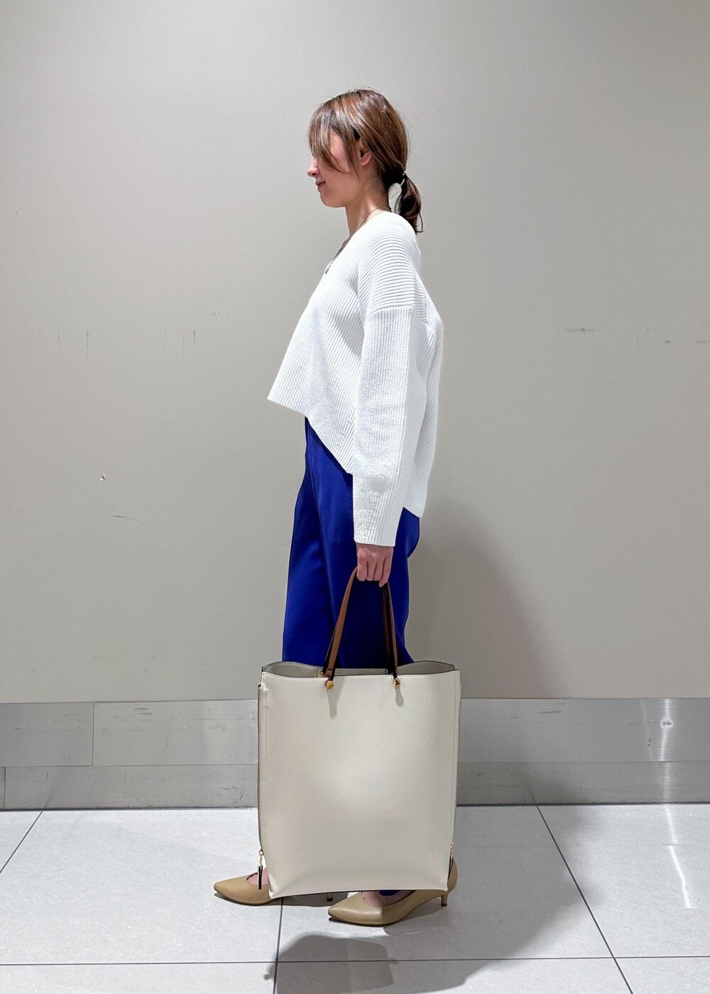 ベージュ系のパンプス、ホワイト系のトートバッグ、ブルー系のその他パンツを着用したレディースの冬コーディネートの2枚目の写真