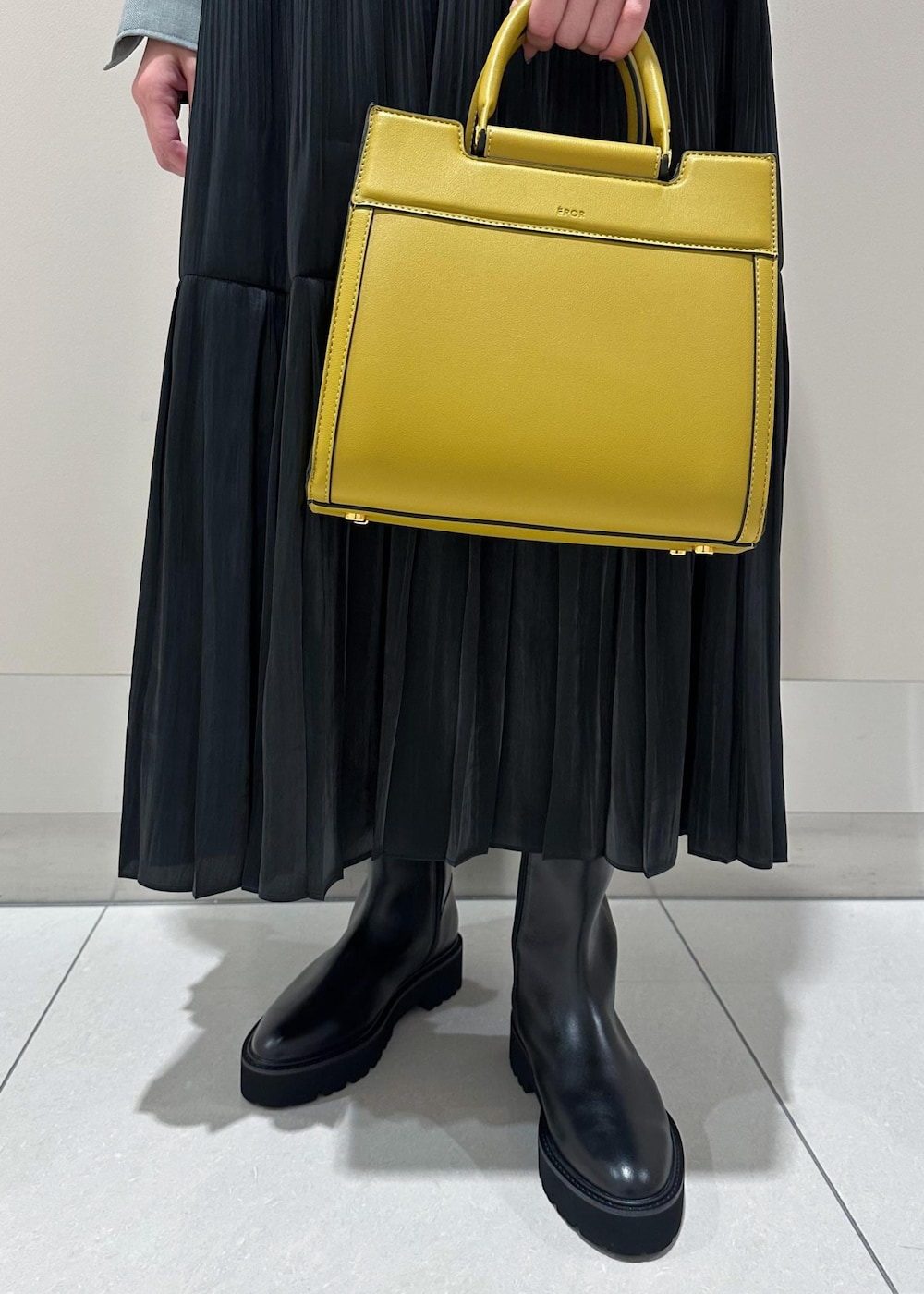 イエロー系のハンドバッグ、グレー系のシャツ/ブラウス、ブラック系のスカートを着用したレディースの秋コーディネートの8枚目の写真