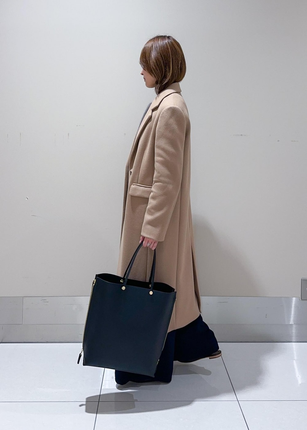 ブラック系のトートバッグ、イエロー系のチェスターコート、ブラウン系のニット/セーターを着用したレディースの秋コーディネートの2枚目の写真