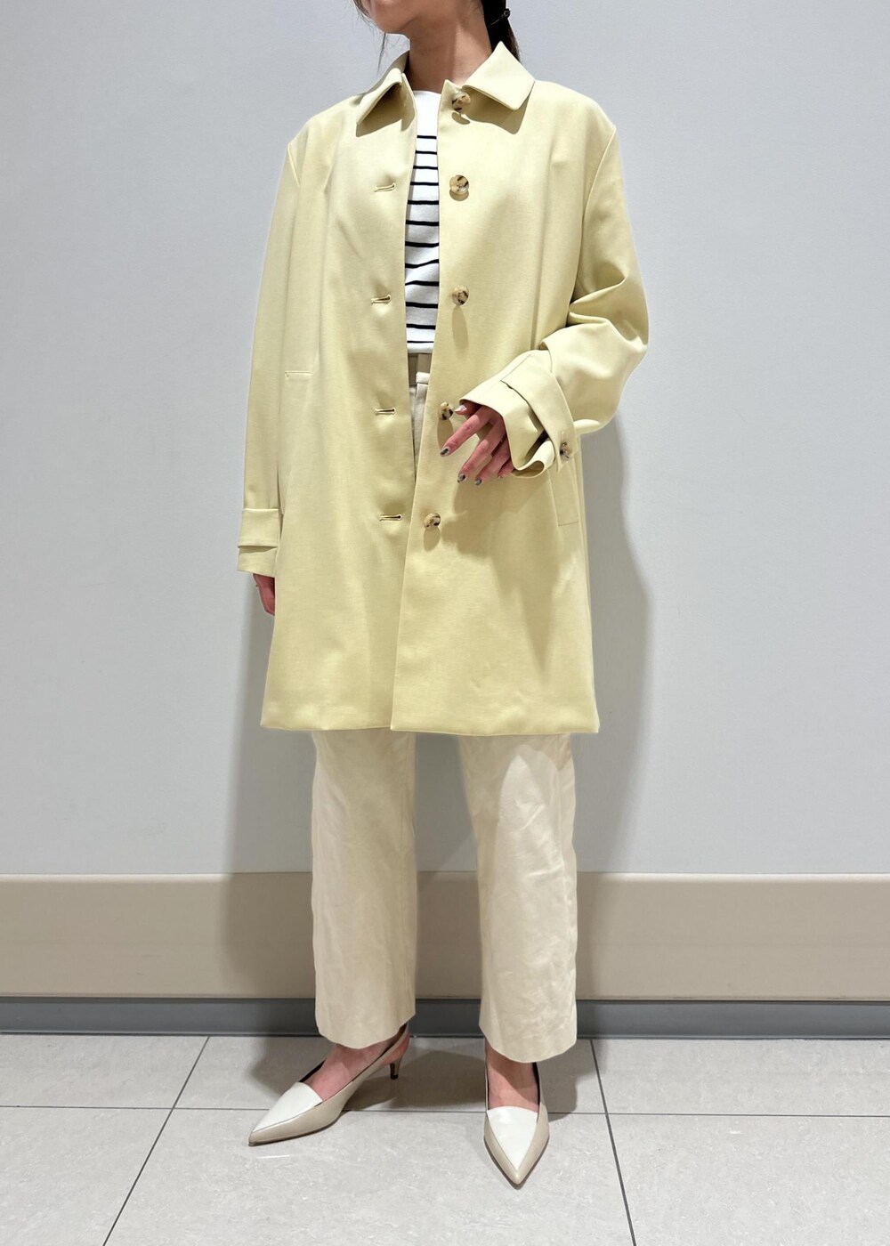 ホワイト系のハンドバッグ、ベージュ系のステンカラーコート、ホワイト系のその他パンツを着用したレディースの春コーディネートの4枚目の写真