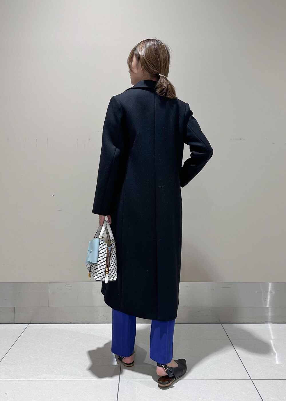 ホワイト系のショルダーバッグ、ブラック系のチェスターコート、グレー系のシャツ/ブラウスを着用したレディースの冬コーディネートの3枚目の写真