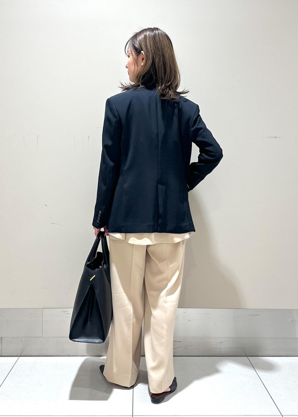 ブルー系のテーラードジャケット、ブラック系のパンプス、ブラック系のトートバッグを着用したレディースの春コーディネートの3枚目の写真