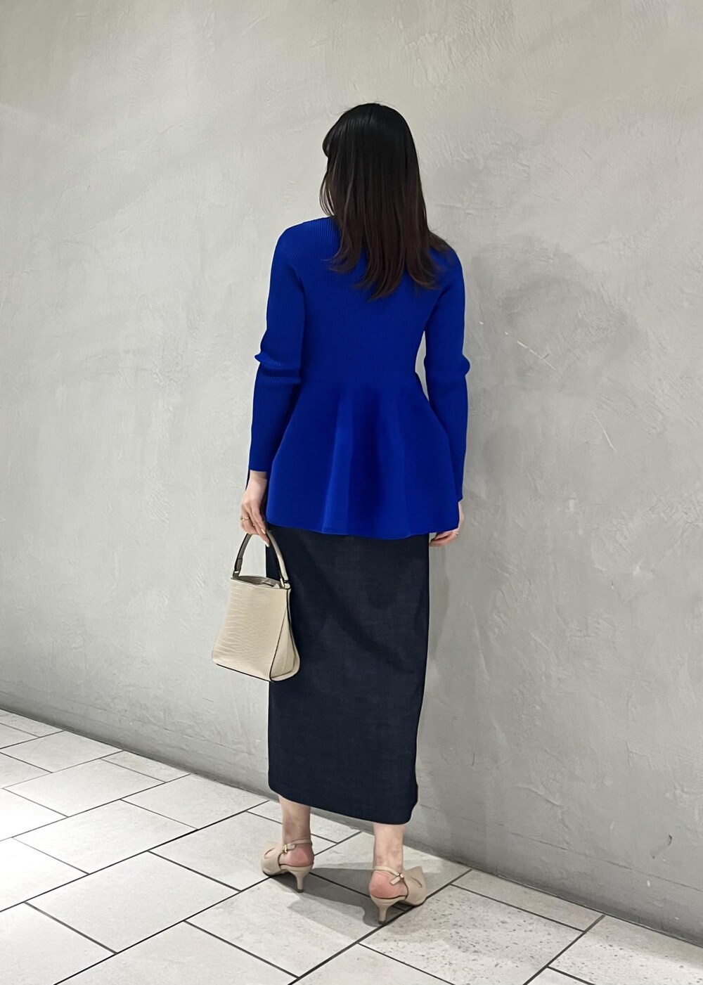 ベージュ系のパンプス、ベージュ系のショルダーバッグ、ブルー系のニット/セーターを着用したレディースの冬コーディネートの3枚目の写真