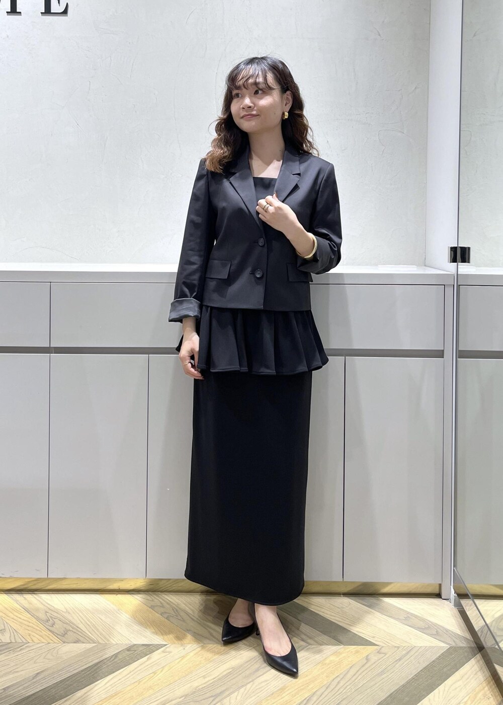 ブラック系のキャミソール、ブラック系のテーラードジャケット、ブラック系のスカートを着用したレディースの秋コーディネートの2枚目の写真