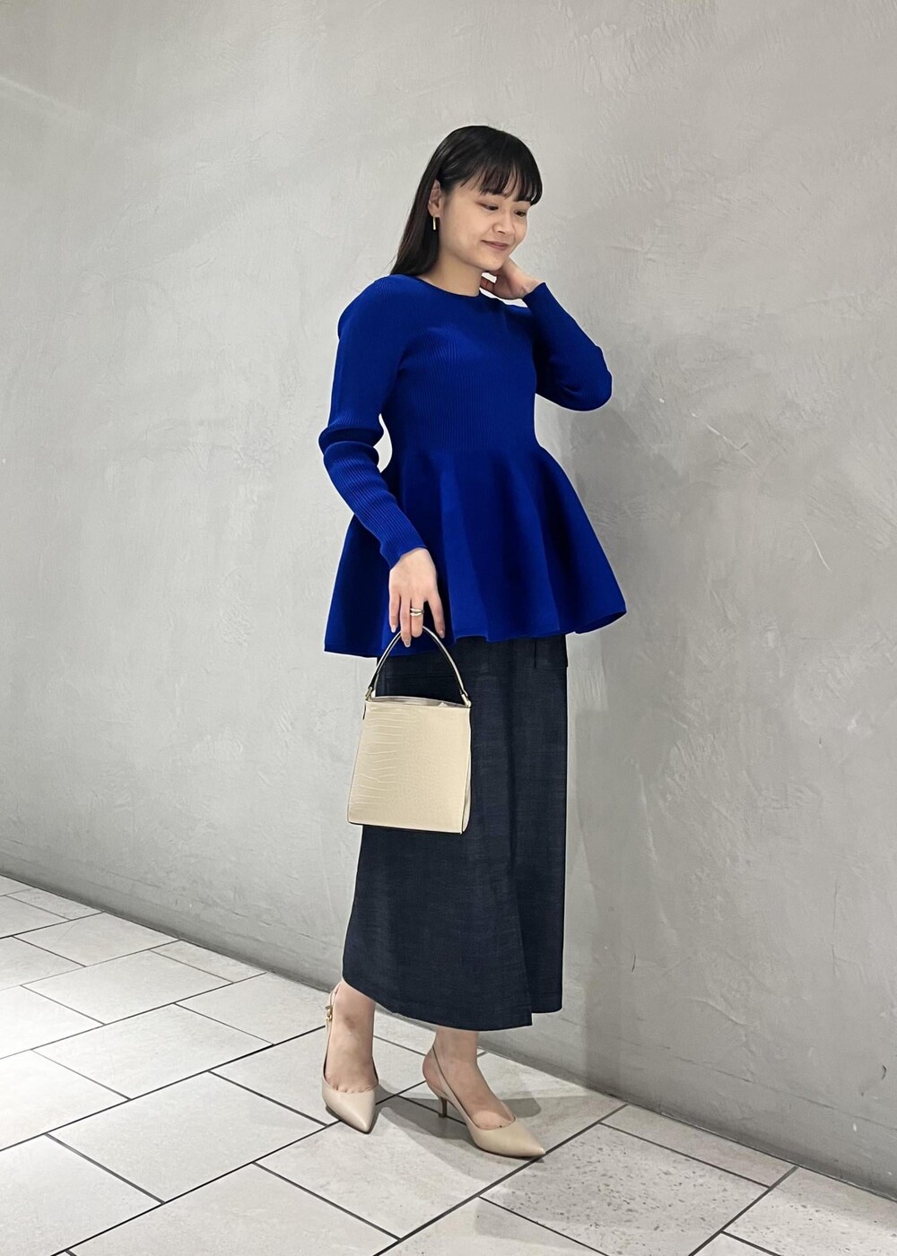ベージュ系のパンプス、ベージュ系のショルダーバッグ、ブルー系のニット/セーターを着用したレディースの冬コーディネートの4枚目の写真