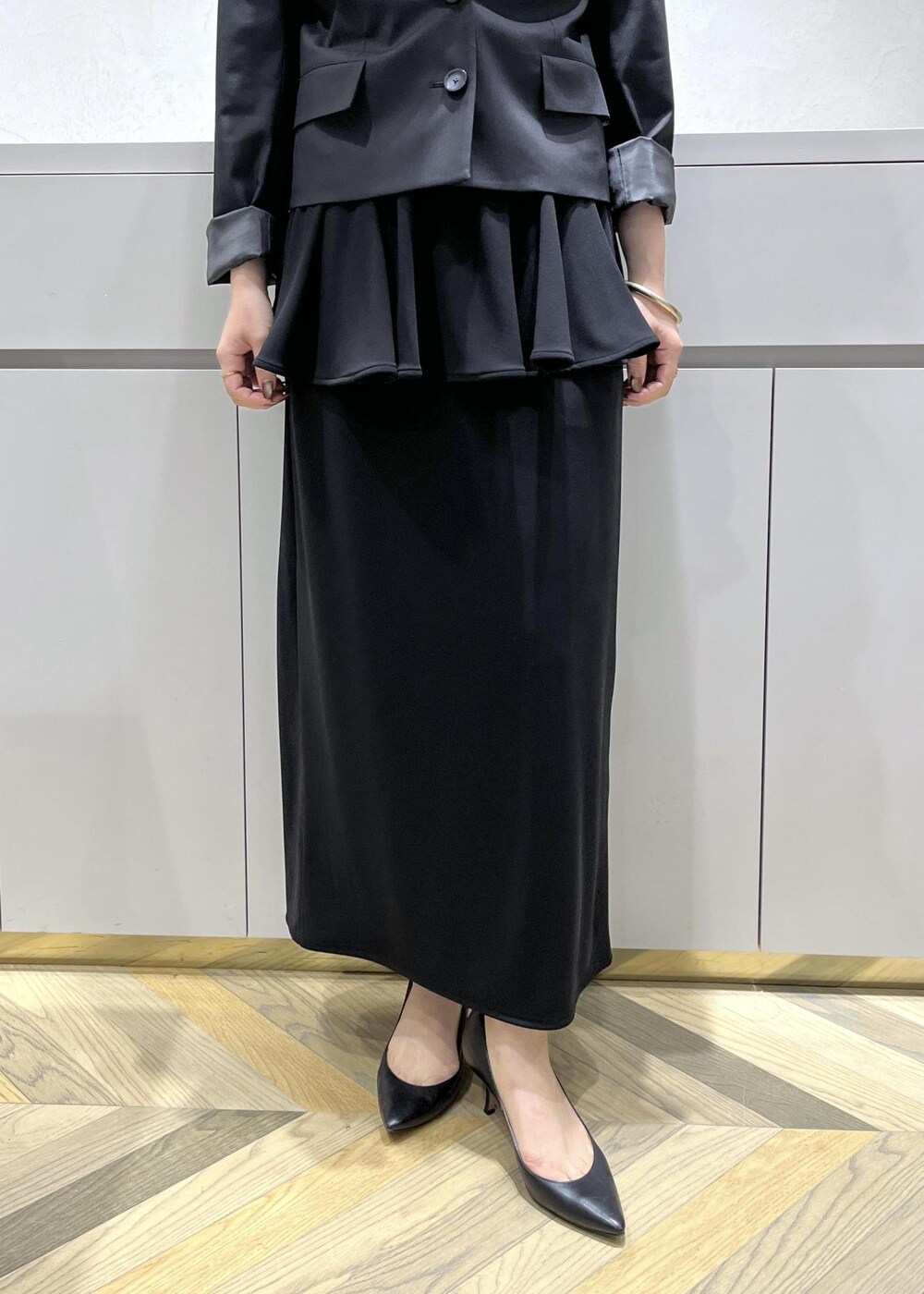 ブラック系のキャミソール、ブラック系のテーラードジャケット、ブラック系のスカートを着用したレディースの秋コーディネートの7枚目の写真
