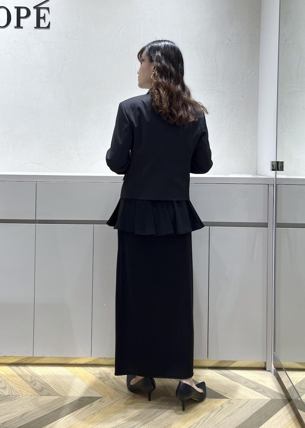 ブラック系のキャミソール、ブラック系のテーラードジャケット、ブラック系のスカートを着用したレディースの秋コーディネートの4枚目の写真