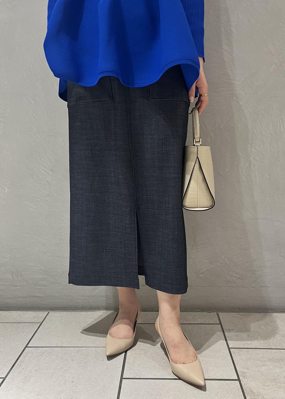 ベージュ系のパンプス、ベージュ系のショルダーバッグ、ブルー系のニット/セーターを着用したレディースの冬コーディネートの6枚目の写真