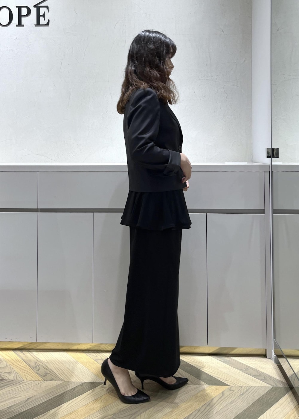 ブラック系のキャミソール、ブラック系のテーラードジャケット、ブラック系のスカートを着用したレディースの秋コーディネートの3枚目の写真