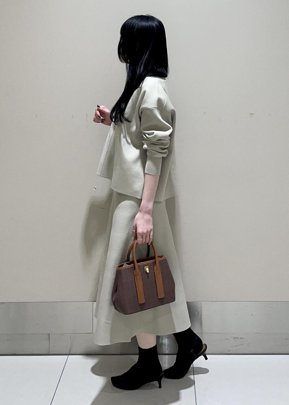 ブラウン系のショルダーバッグ、ベージュ系のスカート、ベージュ系のニット/セーターを着用したレディースの冬コーディネートの2枚目の写真