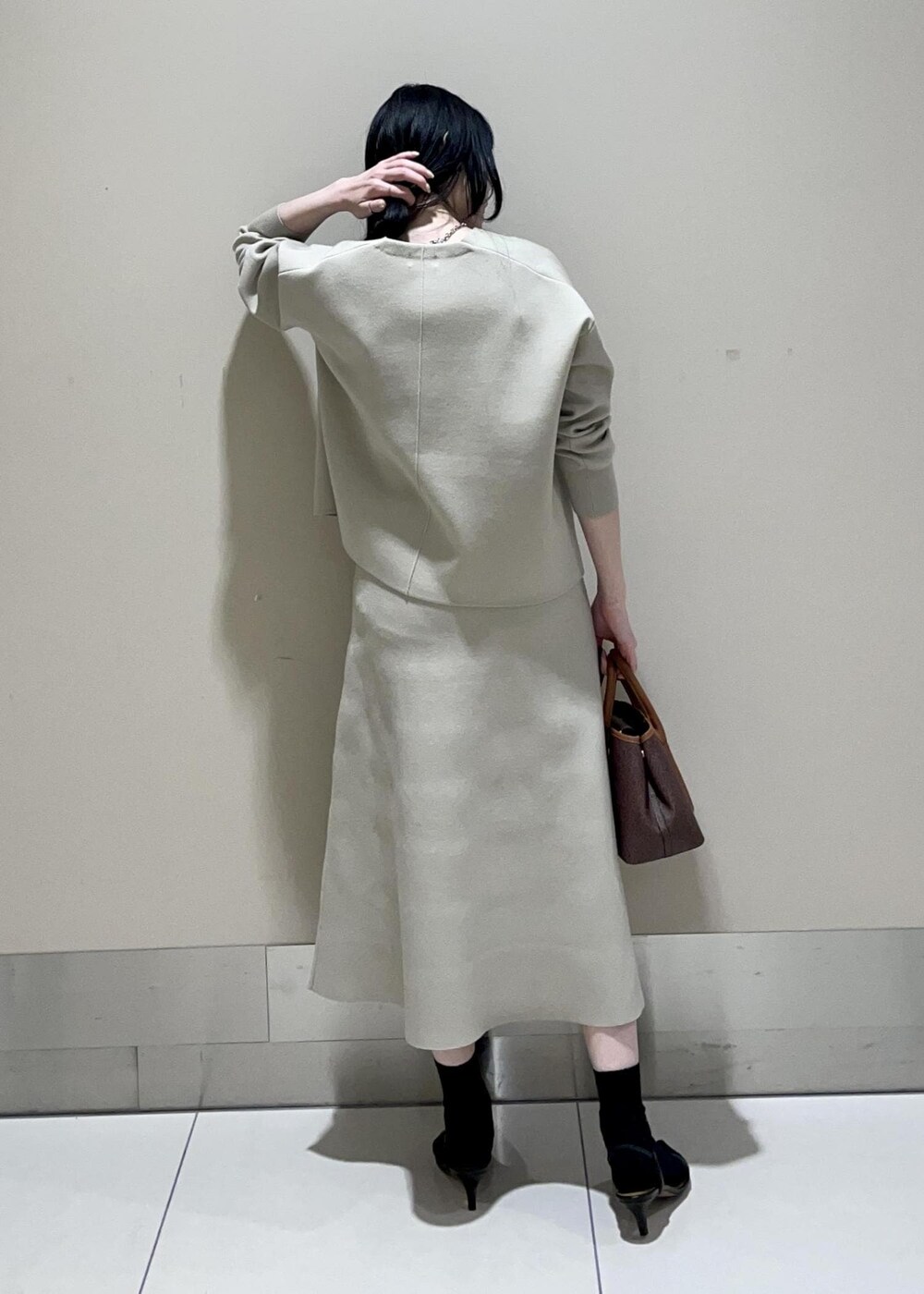 ブラウン系のショルダーバッグ、ベージュ系のスカート、ベージュ系のニット/セーターを着用したレディースの冬コーディネートの3枚目の写真