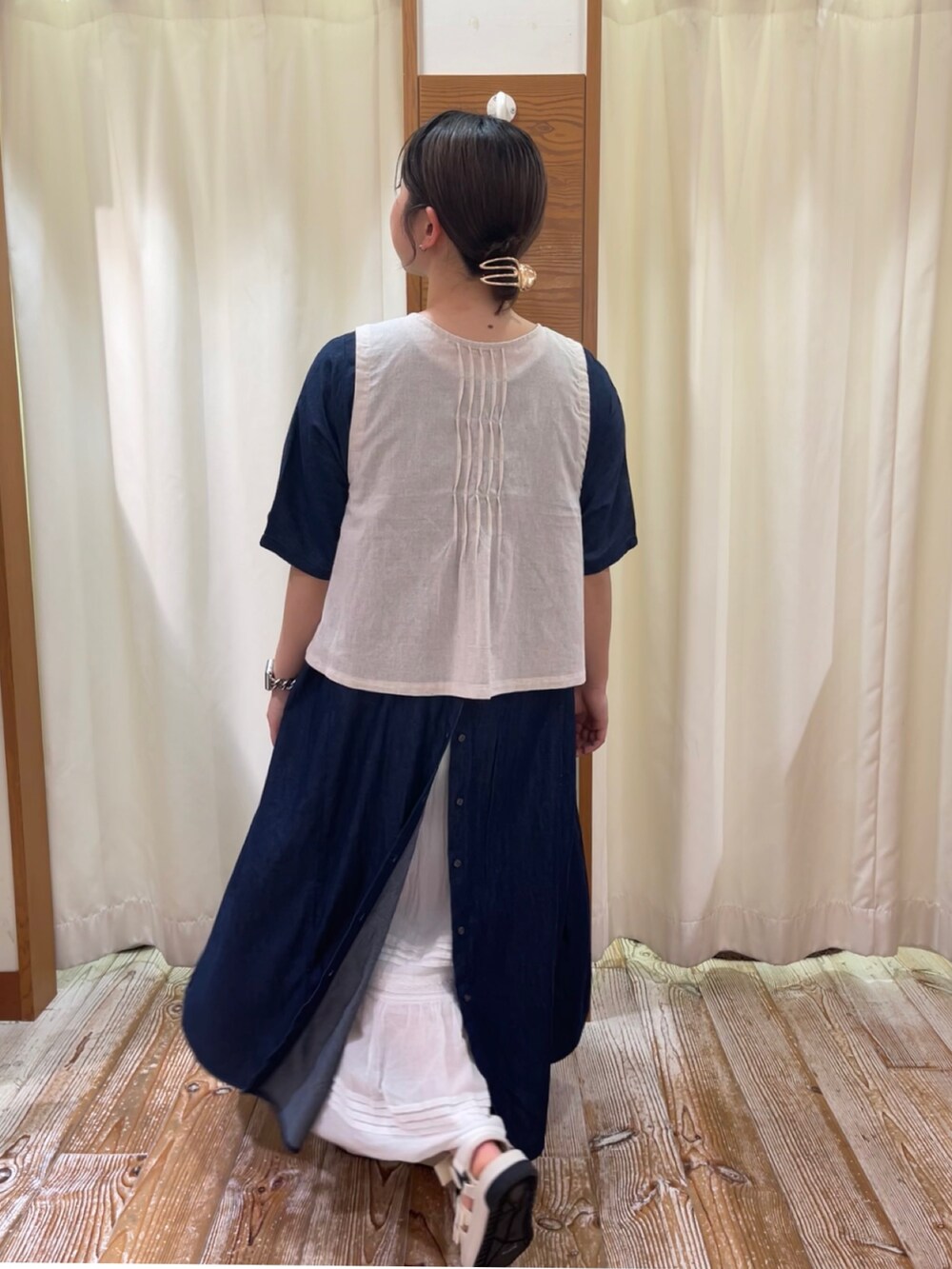 ブルー系のワンピース、ホワイト系のベスト、ホワイト系のサンダルを着用したレディースの夏コーディネートの2枚目の写真