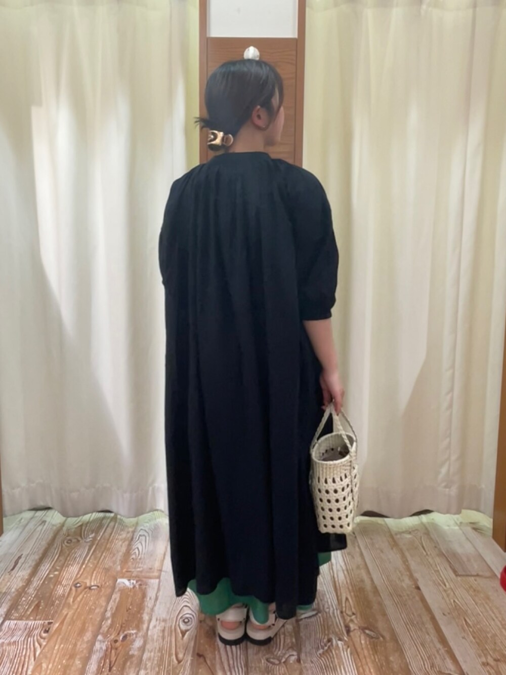 ブラック系のワンピース、グリーン系のスカート、ホワイト系のサンダルを着用したレディースの夏コーディネートの2枚目の写真