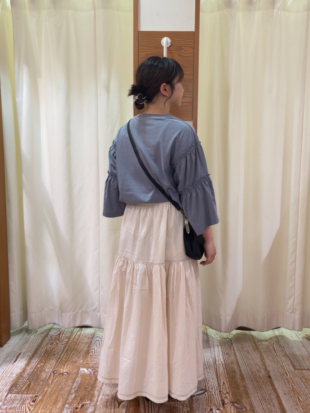 ブルー系のTシャツ/カットソー、ホワイト系のスカート、ブラック系のハンドバッグを着用したレディースの夏コーディネートの2枚目の写真