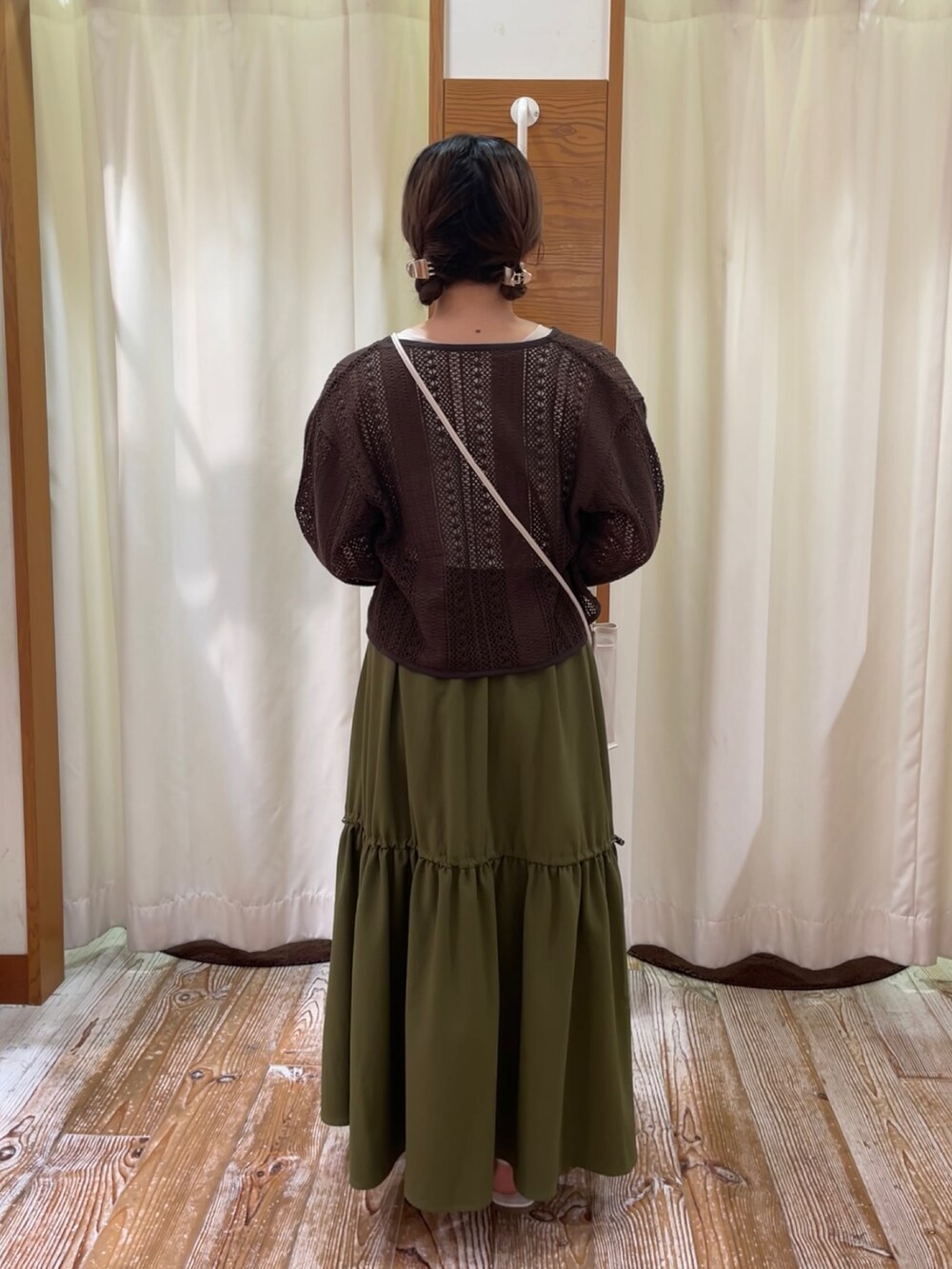 グリーン系のスカート、ブラウン系のカーディガン/ボレロ、ホワイト系のタンクトップを着用したレディースの夏コーディネートの3枚目の写真