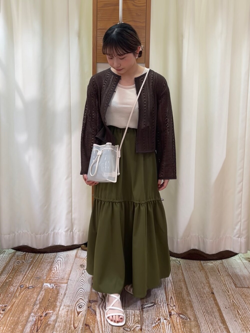 グリーン系のスカート、ブラウン系のカーディガン/ボレロ、ホワイト系のタンクトップを着用したレディースの夏コーディネートの2枚目の写真