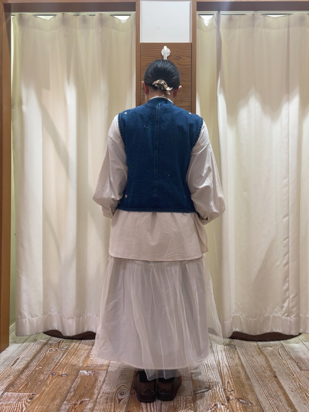 ブルー系のベスト、ホワイト系のチュニック、ホワイト系のスカートを着用したレディースの冬コーディネートの2枚目の写真