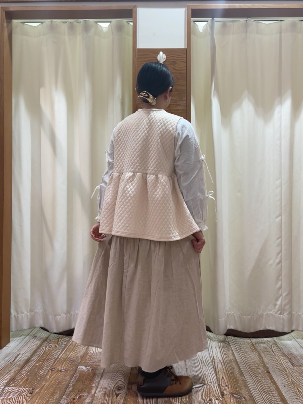 ホワイト系のベスト、ホワイト系のシャツ/ブラウス、ベージュ系のスカートを着用したレディースの冬コーディネートの2枚目の写真