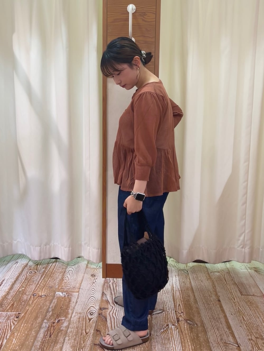 レッド系のカーディガン/ボレロ、ベージュ系のキャミソール、ブルー系のデニムパンツを着用したレディースの夏コーディネートの2枚目の写真