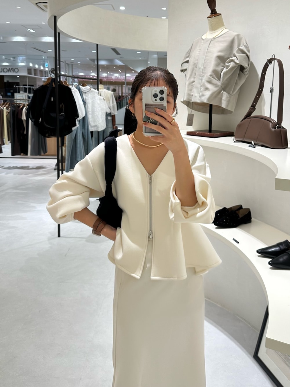 ホワイト系のカーディガン/ボレロ、ホワイト系のスカート、ブラック系のパンプスを着用したレディースの秋コーディネートの2枚目の写真