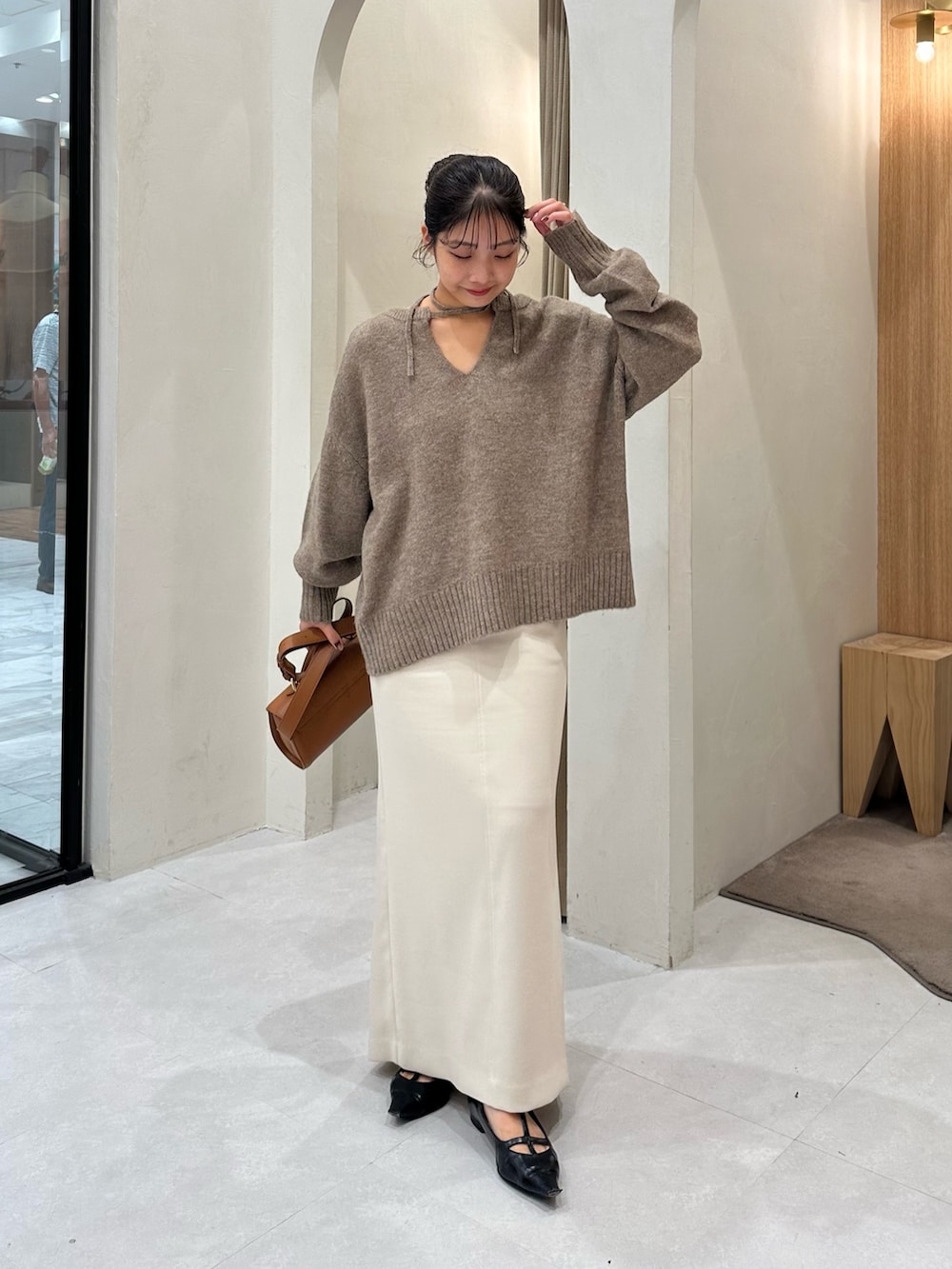 ブラウン系のニット/セーター、ホワイト系のスカート、ブラック系のパンプスを着用したレディースの秋コーディネートの2枚目の写真