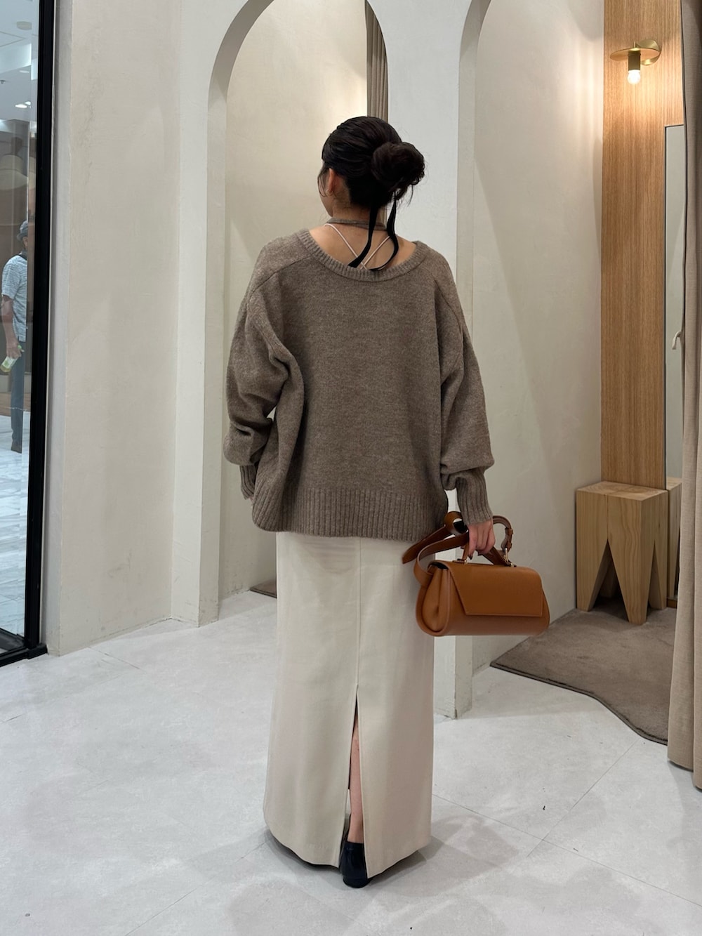 ブラウン系のニット/セーター、ホワイト系のスカート、ブラック系のパンプスを着用したレディースの秋コーディネートの3枚目の写真