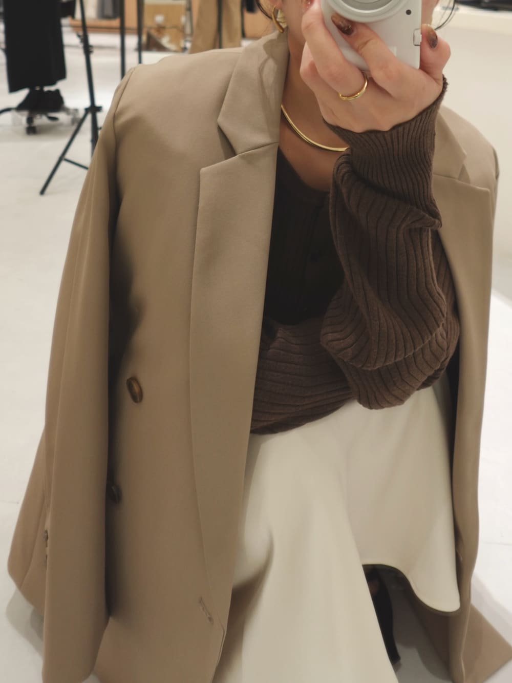 ベージュ系のテーラードジャケット、ホワイト系のスカート、ブラック系のパンプスを着用したレディースの秋コーディネートの4枚目の写真