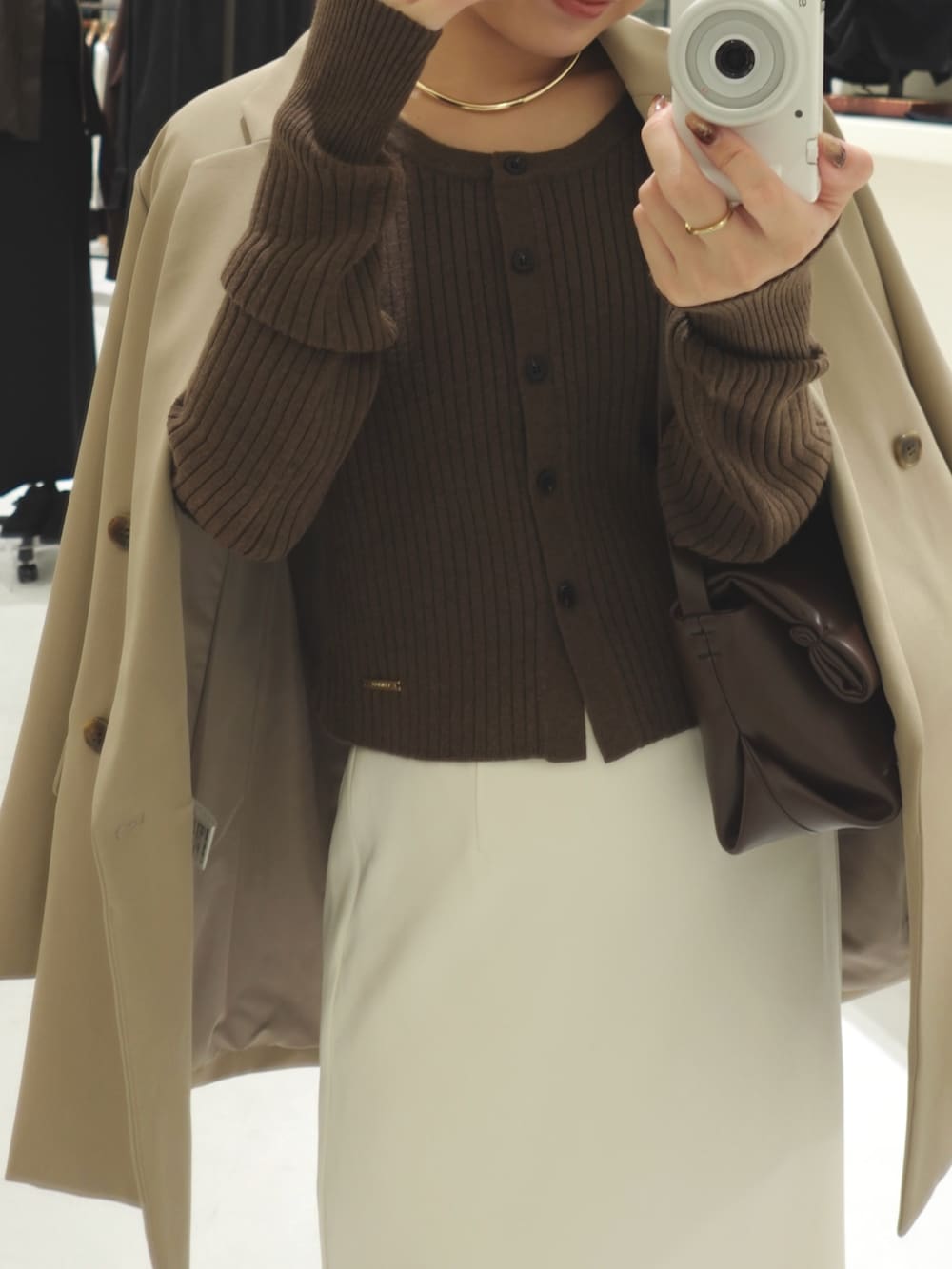 ベージュ系のテーラードジャケット、ホワイト系のスカート、ブラック系のパンプスを着用したレディースの秋コーディネートの2枚目の写真