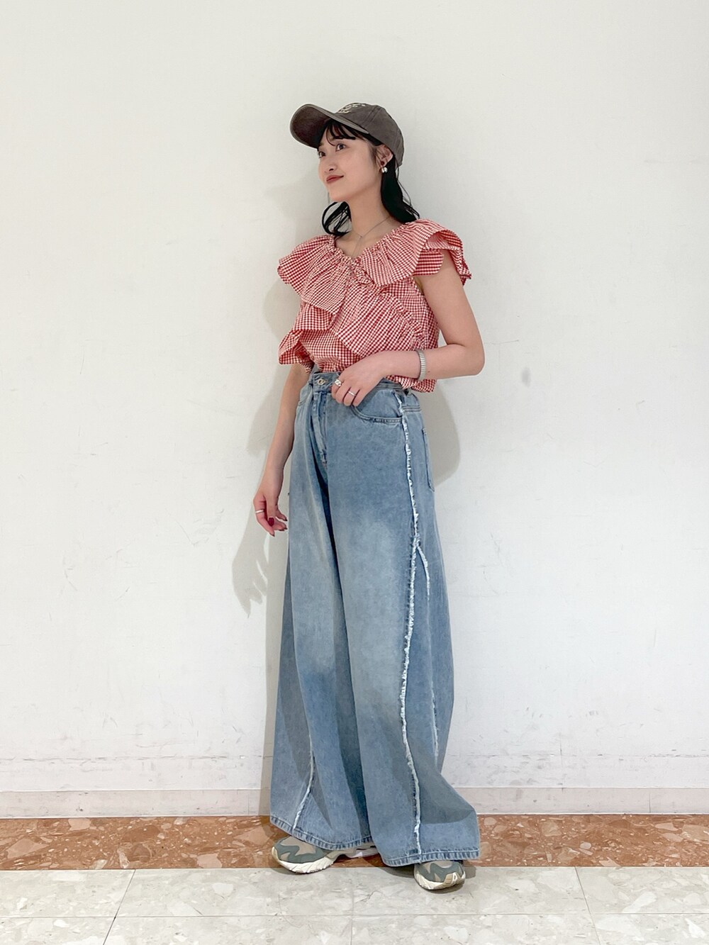 レッド系のシャツ/ブラウス、ブルー系のデニムパンツ、ブラウン系のキャップを着用したレディースの春コーディネートの2枚目の写真