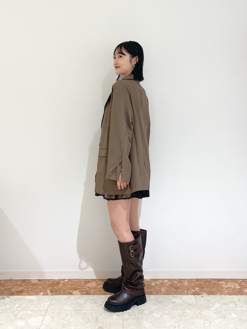 ブラウン系のテーラードジャケット、ブラック系のワンピース、ブラウン系のブーツを着用したレディースの秋コーディネートの4枚目の写真