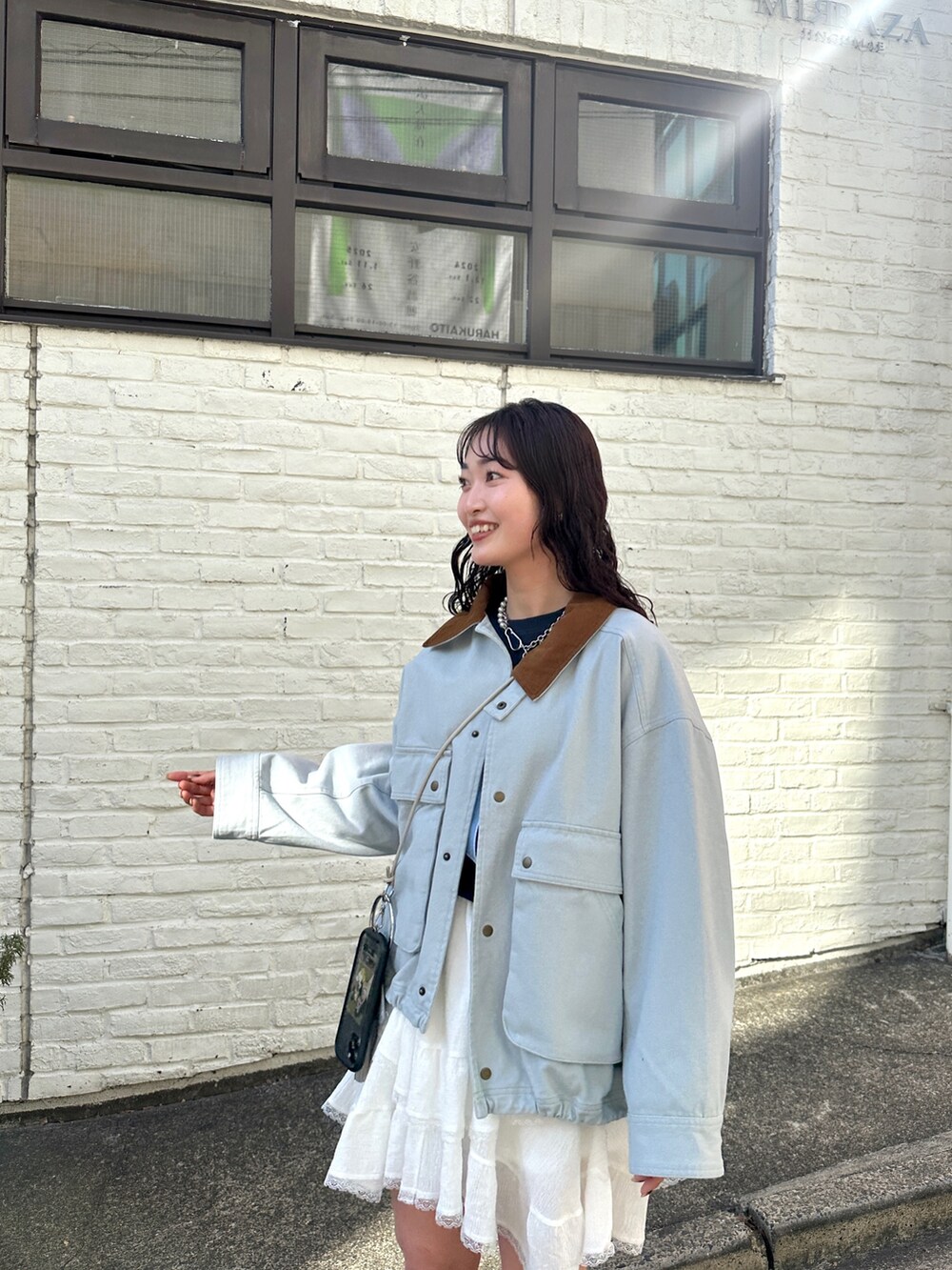 ブルー系のブルゾン、ホワイト系のスカート、ブルー系のTシャツ/カットソーを着用したレディースの春コーディネートの2枚目の写真