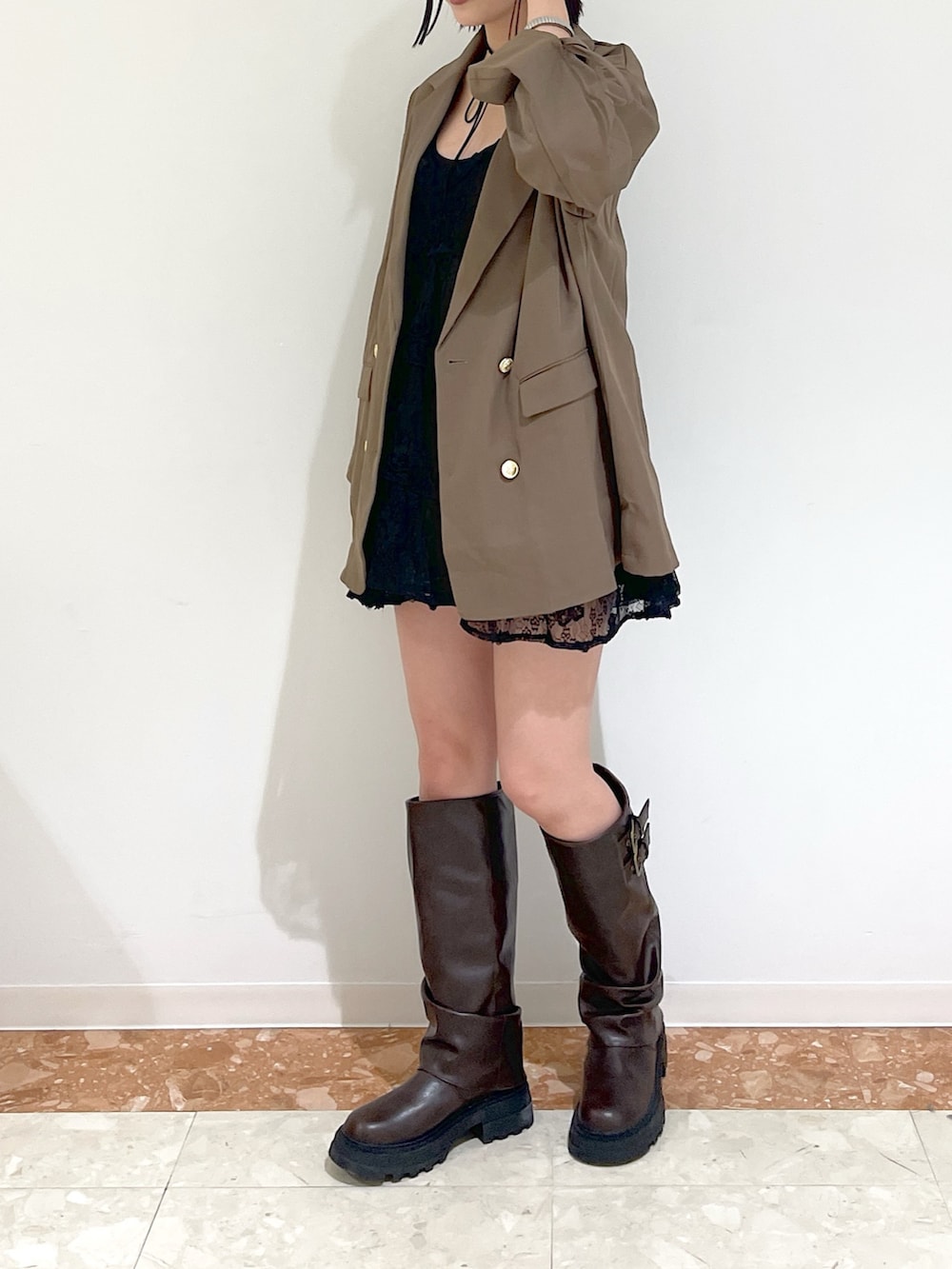 ブラウン系のテーラードジャケット、ブラック系のワンピース、ブラウン系のブーツを着用したレディースの秋コーディネートの3枚目の写真