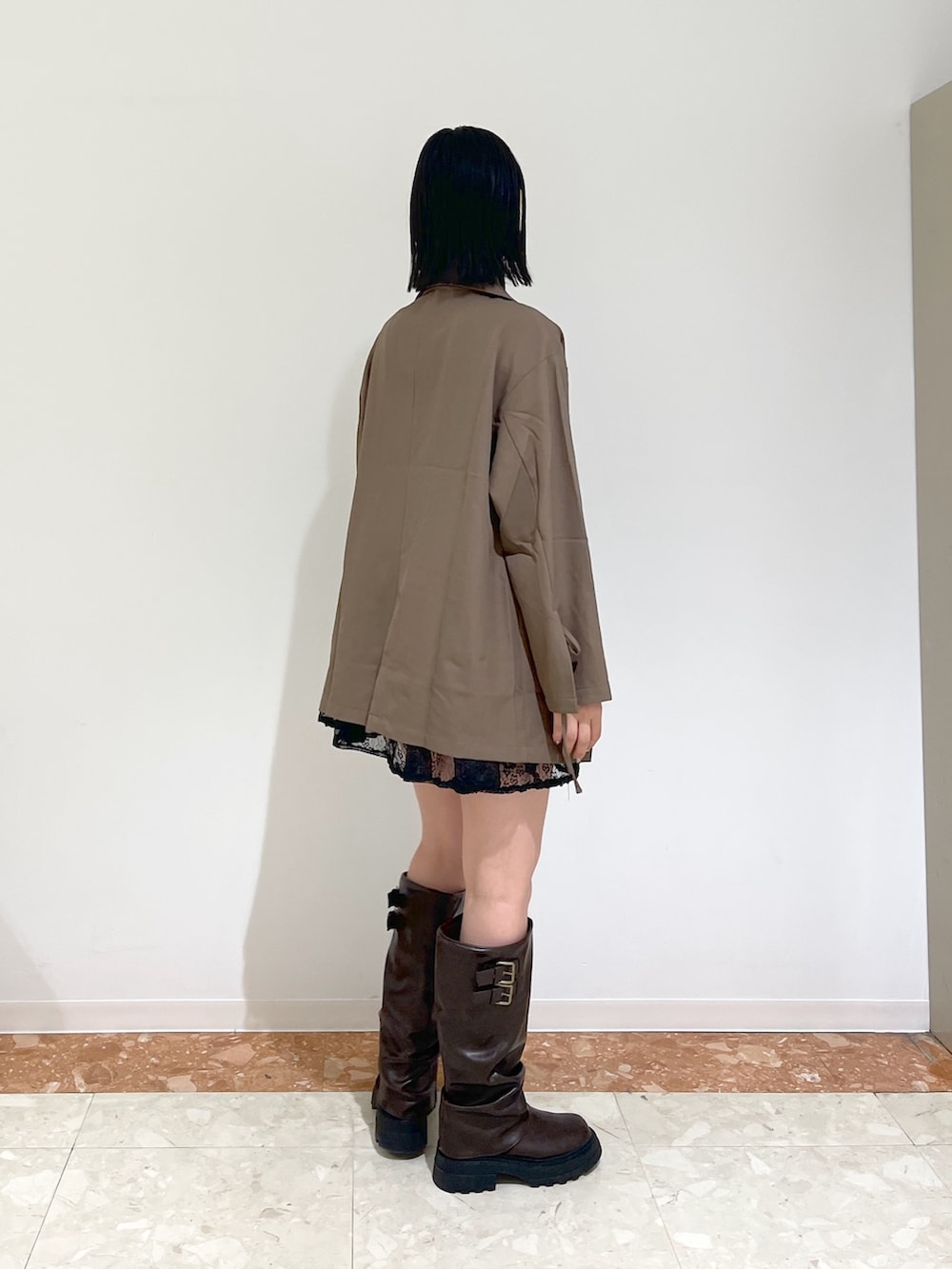 ブラウン系のテーラードジャケット、ブラック系のワンピース、ブラウン系のブーツを着用したレディースの秋コーディネートの2枚目の写真