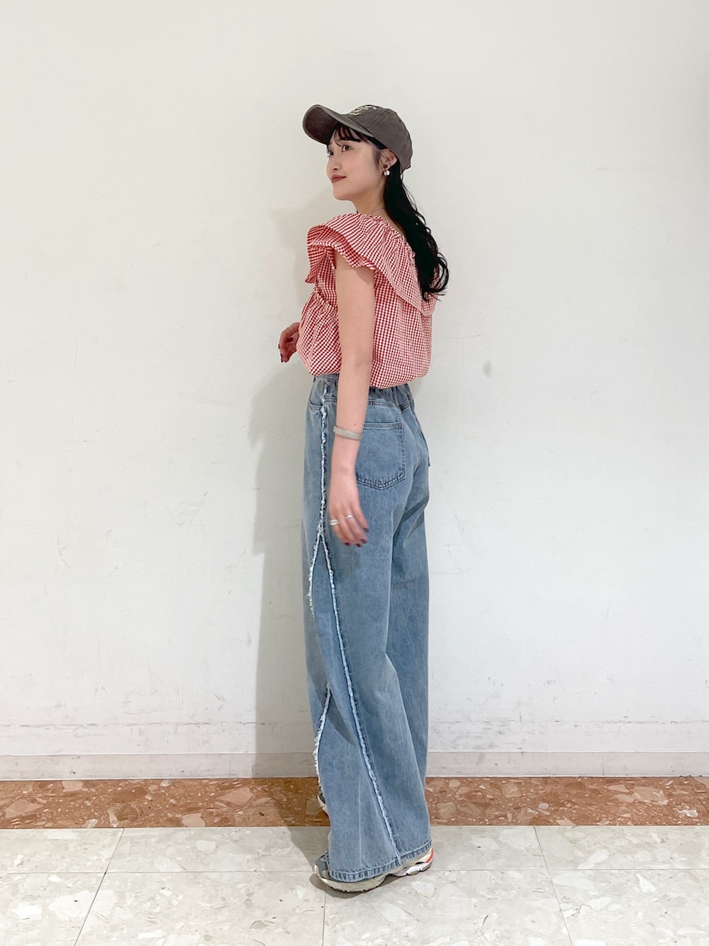 レッド系のシャツ/ブラウス、ブルー系のデニムパンツ、ブラウン系のキャップを着用したレディースの春コーディネートの3枚目の写真