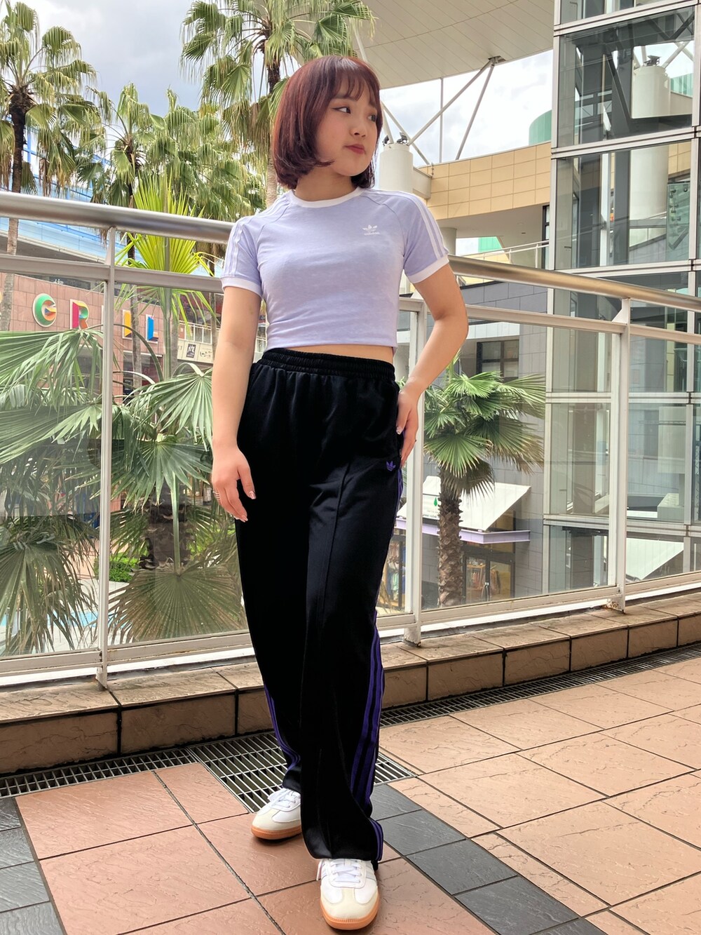 パープル系のトップス、ブラック系のスウェットパンツ、ホワイト系のスニーカーを着用したレディースの春コーディネートの3枚目の写真