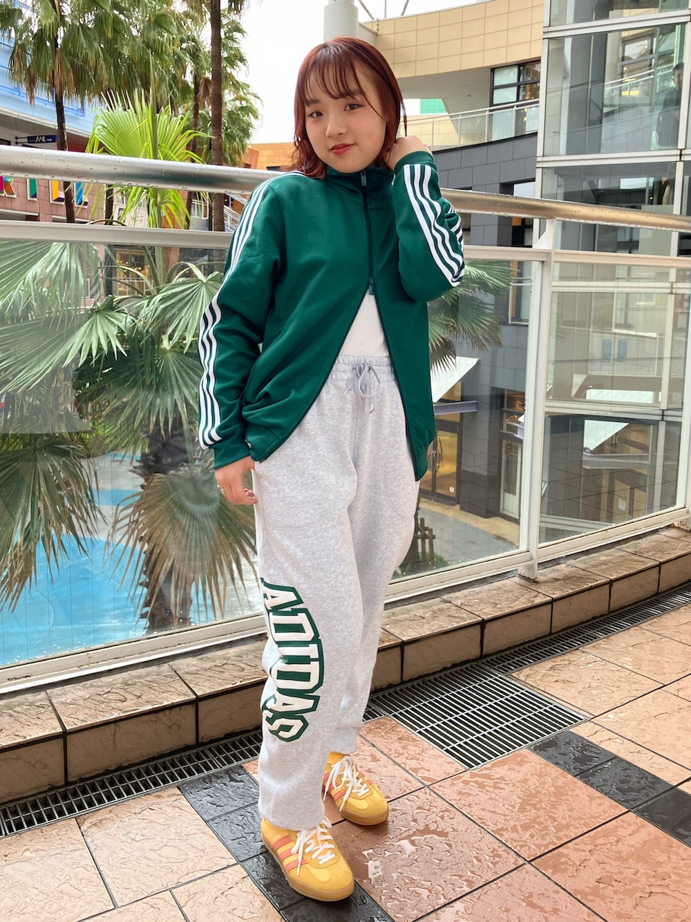 オレンジ系のスニーカー、グリーン系のジャージ、グレー系のスウェットパンツを着用したレディースの春コーディネートの3枚目の写真