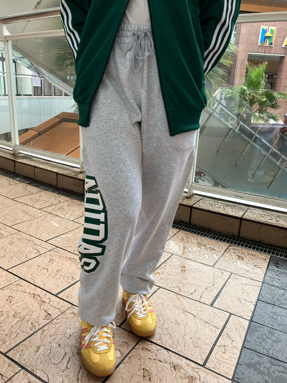 オレンジ系のスニーカー、グリーン系のジャージ、グレー系のスウェットパンツを着用したレディースの春コーディネートの2枚目の写真