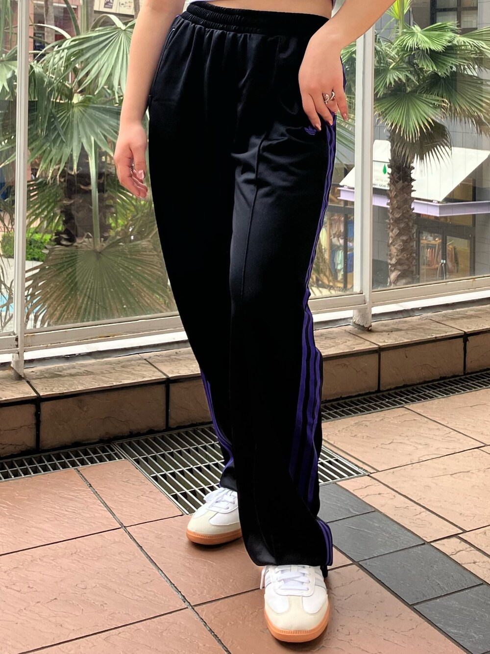 パープル系のトップス、ブラック系のスウェットパンツ、ホワイト系のスニーカーを着用したレディースの春コーディネートの2枚目の写真