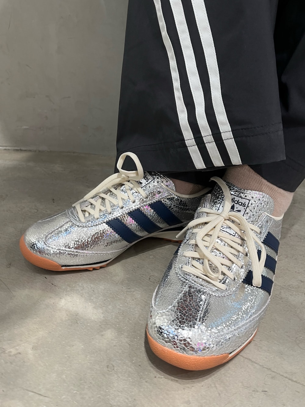 シルバー系のスニーカー、ブラック系のスウェットパンツ、ブラック系のナイロンジャケットを着用したレディースの夏コーディネートの5枚目の写真