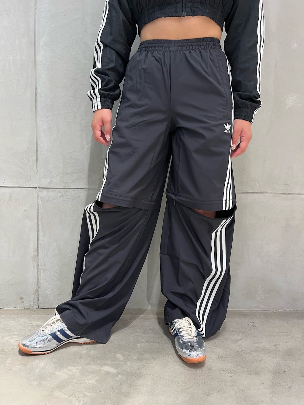 シルバー系のスニーカー、ブラック系のスウェットパンツ、ブラック系のナイロンジャケットを着用したレディースの夏コーディネートの2枚目の写真