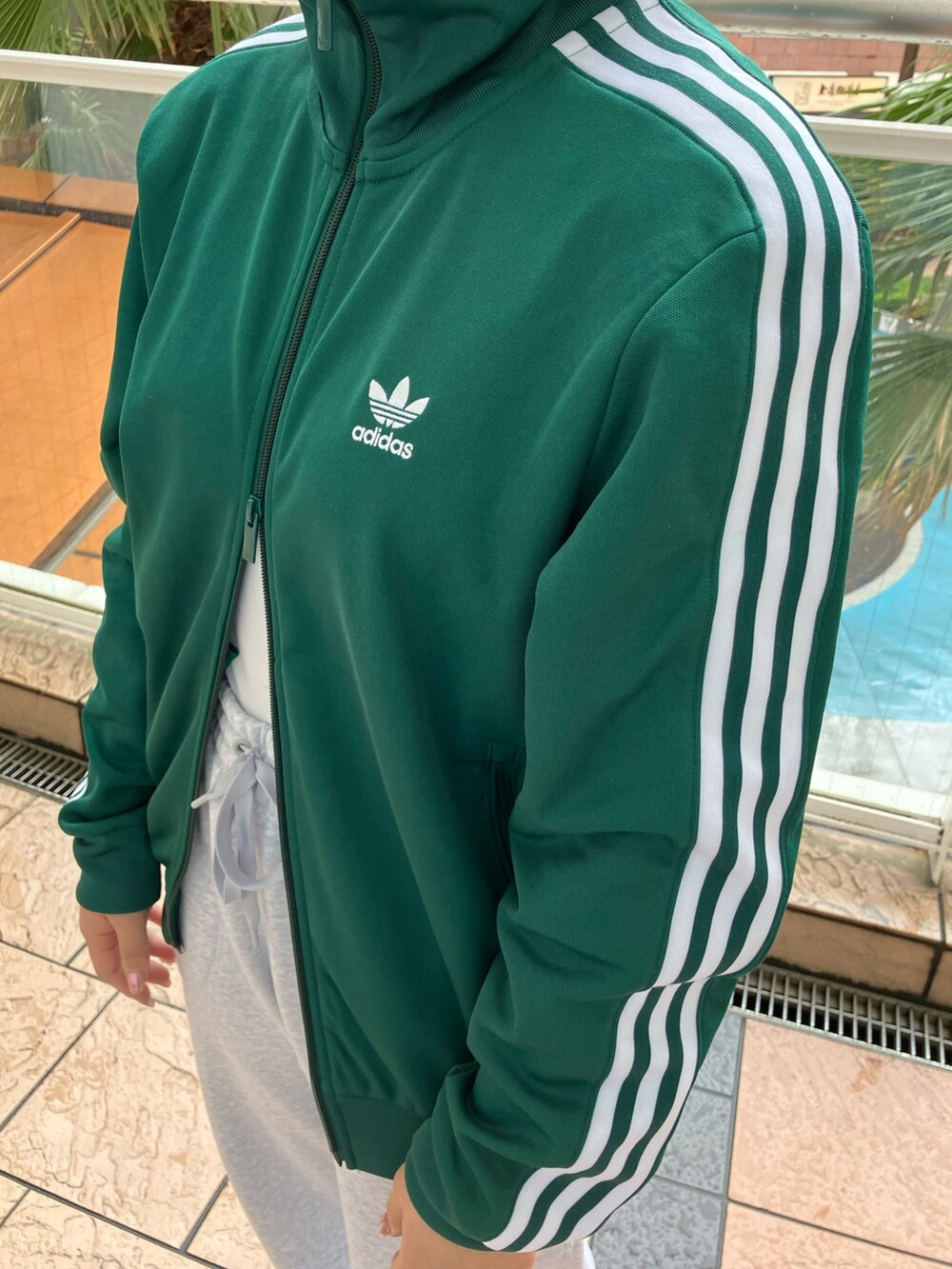 オレンジ系のスニーカー、グリーン系のジャージ、グレー系のスウェットパンツを着用したレディースの春コーディネートの5枚目の写真