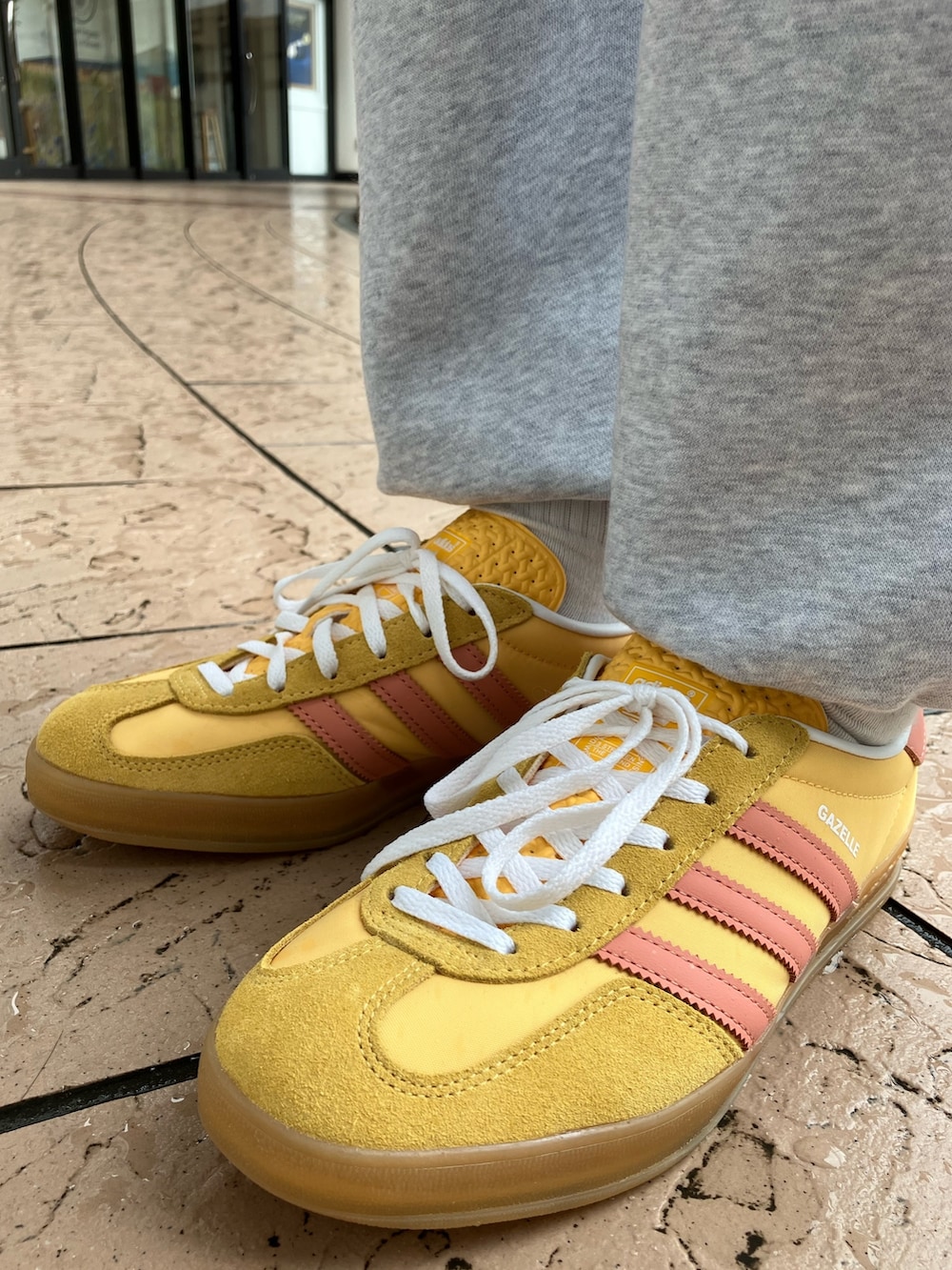 オレンジ系のスニーカー、グリーン系のジャージ、グレー系のスウェットパンツを着用したレディースの春コーディネートの4枚目の写真