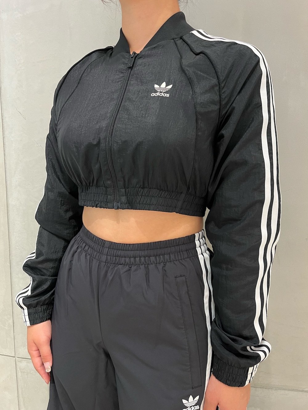 シルバー系のスニーカー、ブラック系のスウェットパンツ、ブラック系のナイロンジャケットを着用したレディースの夏コーディネートの3枚目の写真