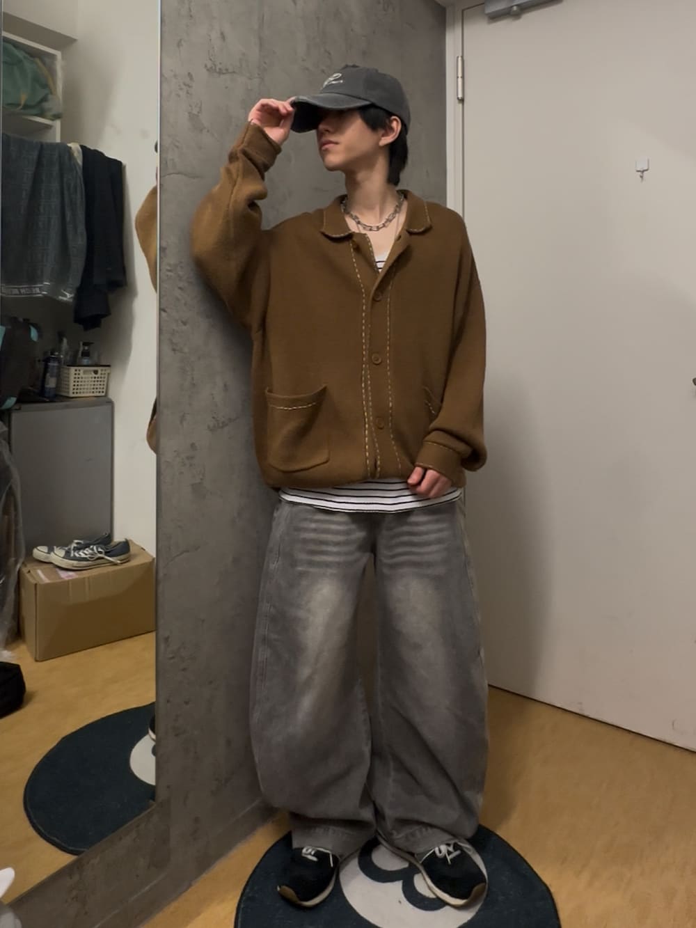 グレー系のデニムパンツ、ベージュ系のカーディガン/ボレロ、グレー系のキャップを着用したメンズの春コーディネートの2枚目の写真