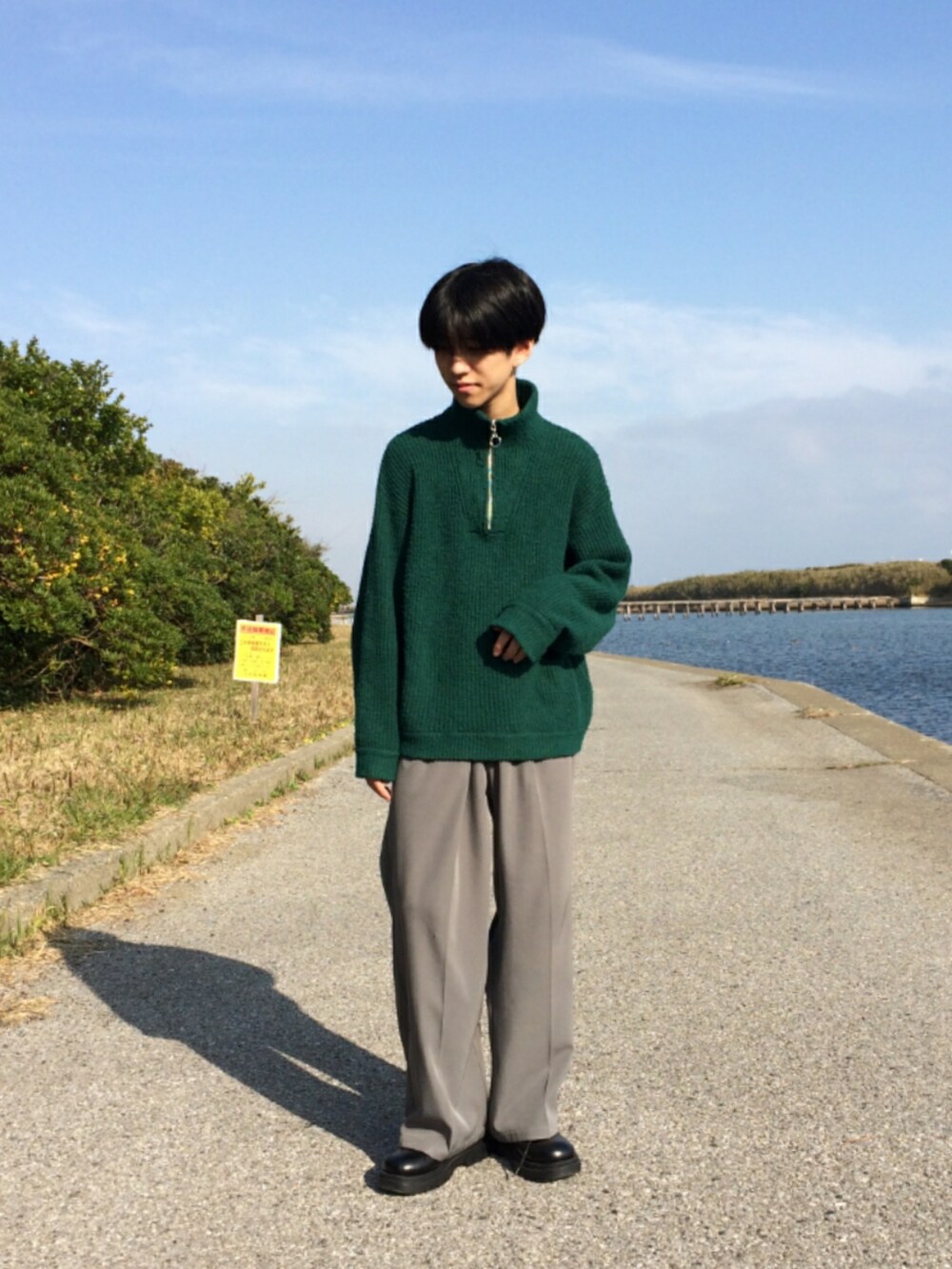 グリーン系のニット/セーター、ブルー系のスラックス、ブラック系のドレスシューズを着用したメンズの冬コーディネートの2枚目の写真